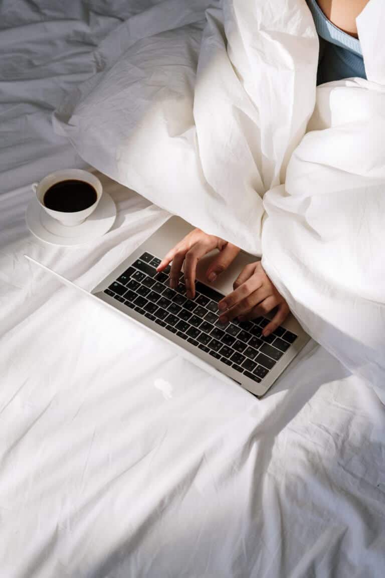 Bild von Person unter Bettdecke, die auf Laptop tippt