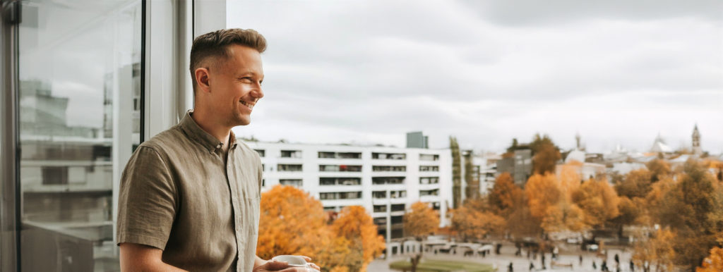 Junger Mann mit Kaffee der auf den Stadtteil schaut